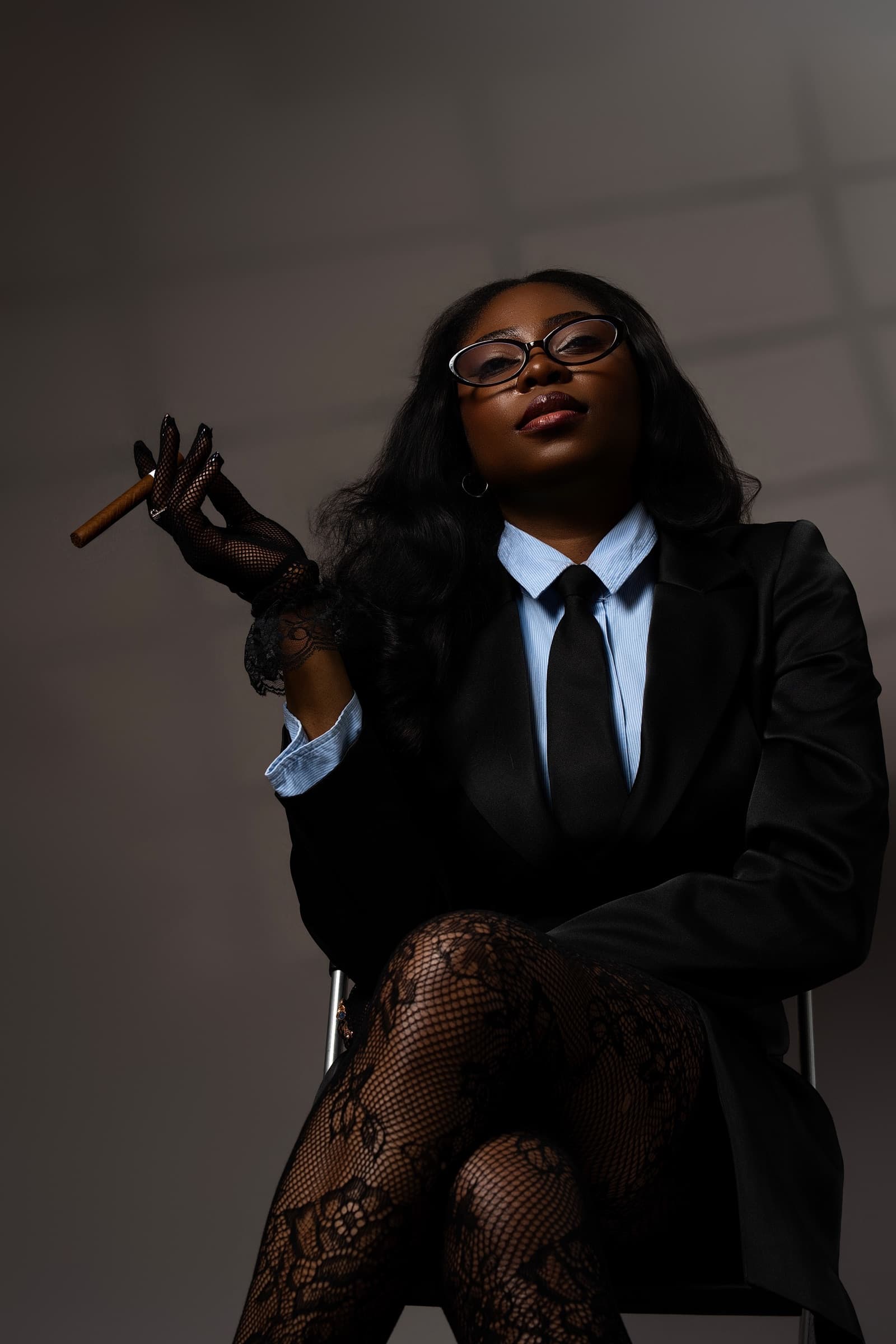 Studio portrait of a woman in a tailored suit holding a cigar